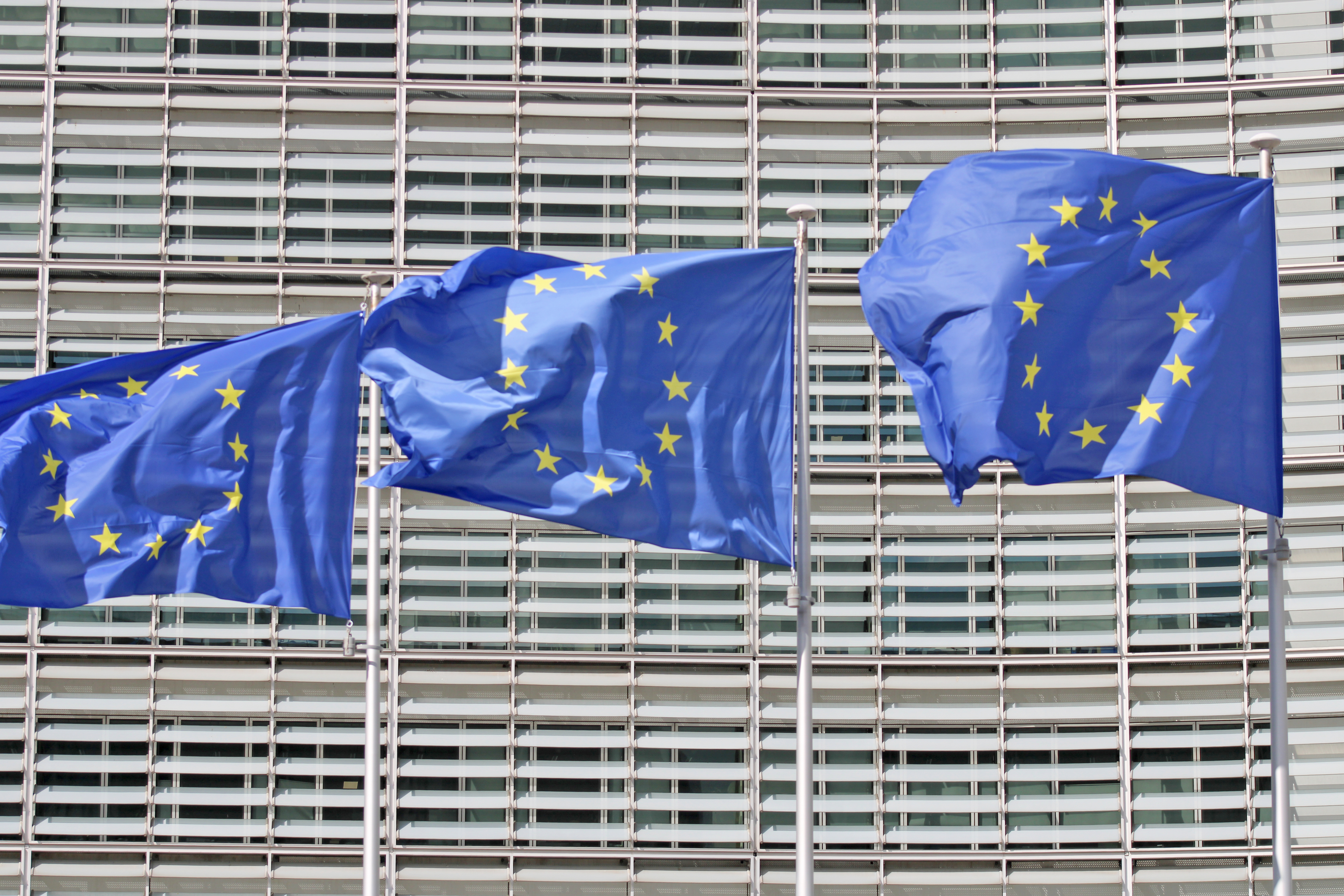 Decorative photo of the EU institutions headquarters in Brussels, place Schuman. It shows EU flags in front of the European Commission Berlaymont building, on a sunny day in September 2026