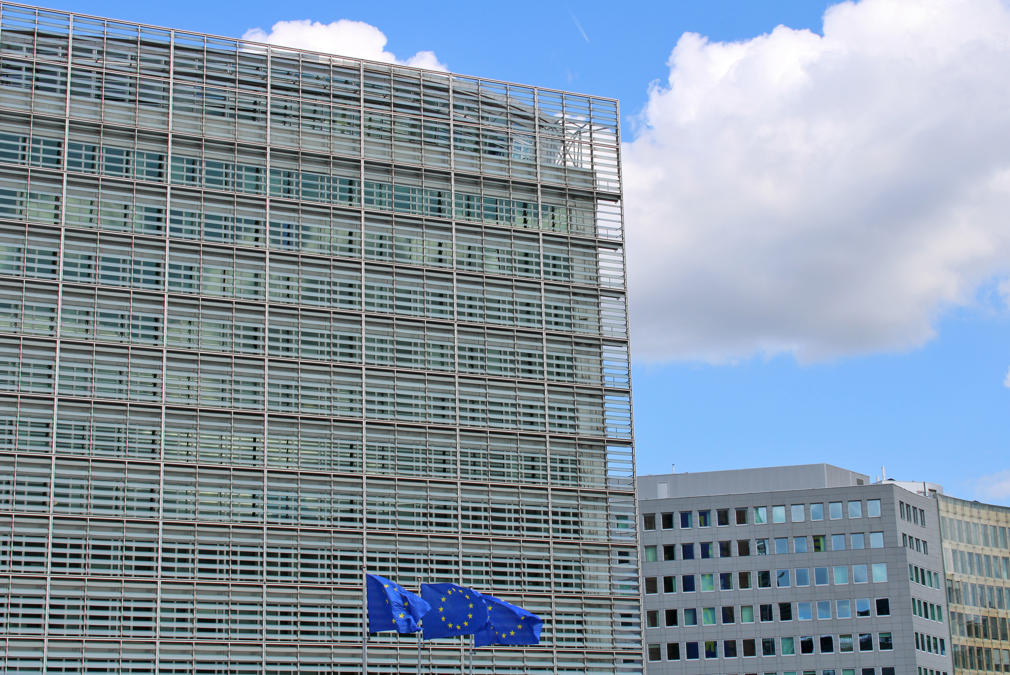 Decorative photo of the EU institutions headquarters in Brussels, place Schuman. It shows EU flags in front of the Berlaymont building on a sunny day in September 2026